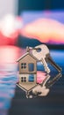 House shaped keys on reflective surface with blurred vibrant colors, symbolizing homeownership at dusk