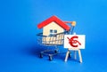 House in a shopping cart and an easel with a red euro arrow down chart. Fall of real estate market. Value cost decrease Royalty Free Stock Photo