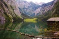 House on the shore of a large Obersee lake in the Alps with logs and stones Royalty Free Stock Photo