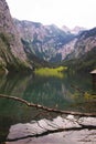 House on the shore of a large Obersee lake in the Alps with logs and stones Royalty Free Stock Photo