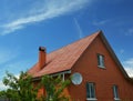 A house of simple construction built from red bricks with a metal gabled roof  a chimney  roof gutters  an attic window  and a Royalty Free Stock Photo