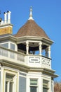 House spire or facade with brown roof and metal tip with white accent banisters and paint and chimney pipes on wooden