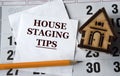 HOUSE STAGING TIPS - words on white paper on the background of a house, pencil and calendar