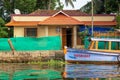 House standing on the edge of the canal and a colourful boat, Kerala, India