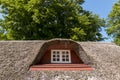 House with standing roof behind a hill, Large stone as a symbol. green grass and large beech trees Royalty Free Stock Photo