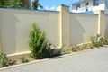 House stone fence with stucco, roses bush and juniper tree