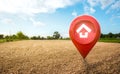 House symbol with location pin icon on empty dry cracked swamp reclamation soil in real estate sale or property investment concept