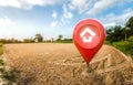 House symbol with location pin icon on empty dry cracked swamp reclamation soil in real estate sale or property investment concept