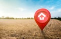 House symbol with location pin icon on empty dry cracked swamp reclamation soil in real estate sale or property investment concept