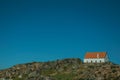 House on top of hilly landscape with bushes and rocks