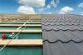 House under construction.Roof with metal tile,screwdriver and roofing iron.