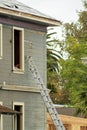 House undergoing repairs on roof and windows with blue wooden facade and white accent paint with ladder Royalty Free Stock Photo