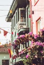 House vtinage flowers on a balcony flower arrangement green facade and pink wall with flags and windows rose roses Royalty Free Stock Photo