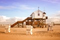 House on wooden stakes on the beach and wicker beach chairs