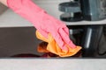 House work. A persons hand in rubber gloves wipes an induction cooker with a rag. Close up