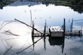 Houseboat with fishing nets in a lake and its image reflected in the water