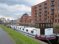 Houseboats moored on the leeds to liverpool canal in the with riverside apartment buildings and the clarence dock area and city
