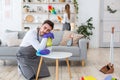 Household chores and tired. Man in apron and gloves sleeping on his knees and table, wife wipes furniture