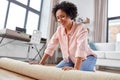 young woman unfolding carpet at home Royalty Free Stock Photo
