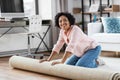 young woman unfolding carpet at home Royalty Free Stock Photo