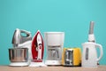 Different household and kitchen appliances on table against color background. Interior element