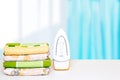 Household laundry ironing. Close-up of a yellow electrical iron and a stack of ironed clothes on white board over blurred curtains Royalty Free Stock Photo