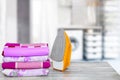 Household laundry ironing. Close-up of a yellow electrical iron and a stack of ironed clothes on white board over blurred curtains Royalty Free Stock Photo