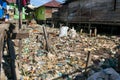 Plastic trash on residential area between houses in asia with a person walking on a wooden way to their home