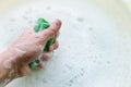 Household sponge in hand on the background of soap suds.