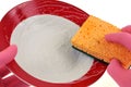 Wash a plate with a double sided sponge on a white background