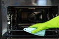 Housekeeper cleaning electric microwave using detergent and rag Royalty Free Stock Photo