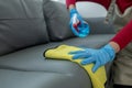 The housekeeper is cleaning the living room inside the house, Cleaning the couch with a towel and sanitizer, Wear rubber gloves