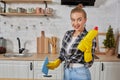 Professional young woman wearing rubber protective yellow gloves holding bottle cleaners in the kitchen. Royalty Free Stock Photo