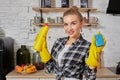 Professional young woman wearing rubber protective yellow gloves holding bottle cleaners in the kitchen. Royalty Free Stock Photo