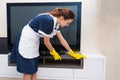 Housekeeper dusting a television and cabinet