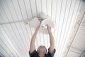 The maidservant is installing and cleaning the ceiling fan. Royalty Free Stock Photo