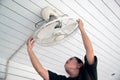 The maidservant is installing and cleaning the ceiling fan. Royalty Free Stock Photo