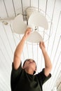 The maidservant is installing and cleaning the ceiling fan.