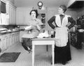 Housekeeper in the kitchen glaring at a young woman eating a cake Royalty Free Stock Photo