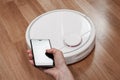 Housekeeper using mobile to control black robotic vacuum cleaner. modern smart cleaning technology housekeeping