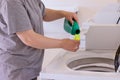 Housekeeper woman pours the liquid powder in washing machine Royalty Free Stock Photo