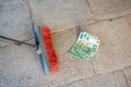 Housekeeping broom sweeping hundredth euro banknote on street