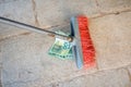 Housekeeping broom sweeping hundredth euro banknote on street