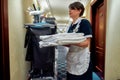 Housekeeping. A hotel maid in uniform standing in front of chambermaid trolley and holding fresh bed-linen. Room service Royalty Free Stock Photo