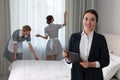 Housekeeping manager with tablet checking maid`s work in hotel bedroom Royalty Free Stock Photo