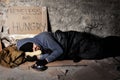 Houseless man sleeping on the street with alms box Royalty Free Stock Photo