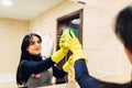 Housemaid cleans the mirror with a cleaning spray Royalty Free Stock Photo