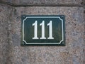 Housenumber 111 on an enamel sign on a stone wall Royalty Free Stock Photo