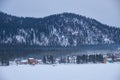 Houses on the bank of frozen Teletskoe lake under the chimney smoke. Iogach, Altai
