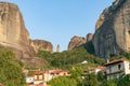 Houses and church in foothills among trees below towering rocks and pinnacles at Meteora